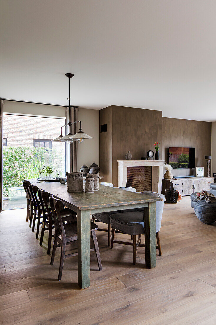 Rustic wooden table with chairs in dining room with fireplace and terrace view