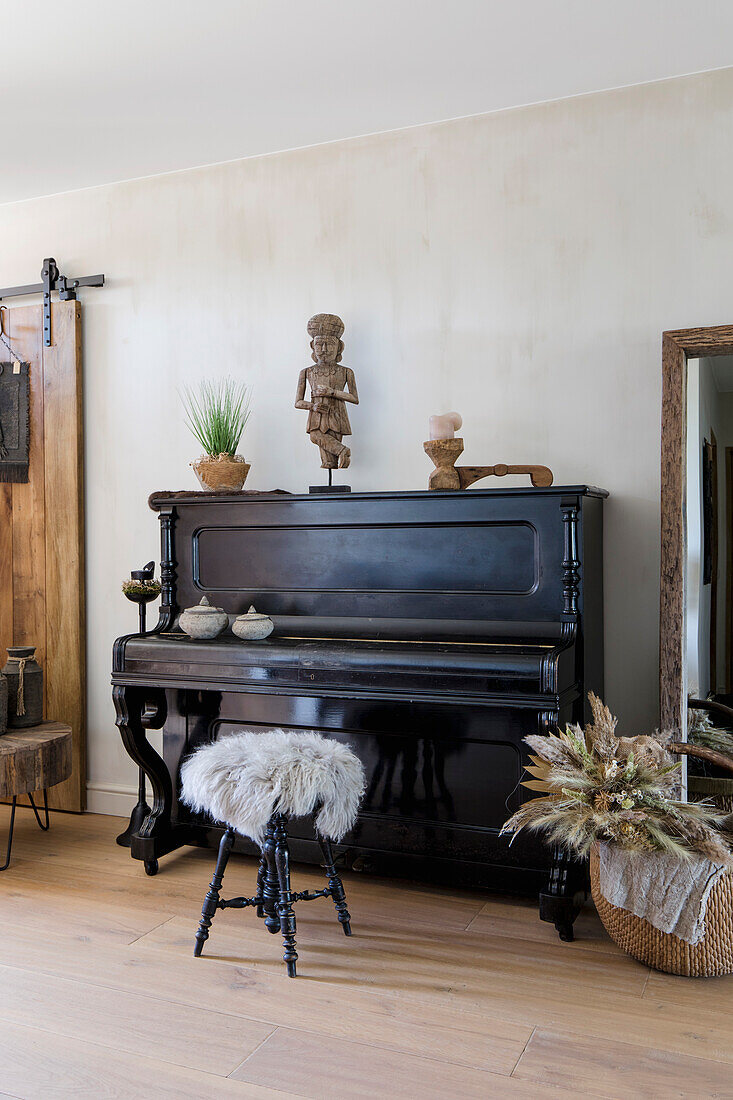 Black piano with stool and ethnic sculptures