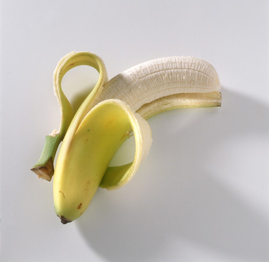 Halb geschälte Banane auf weißem Untergrund