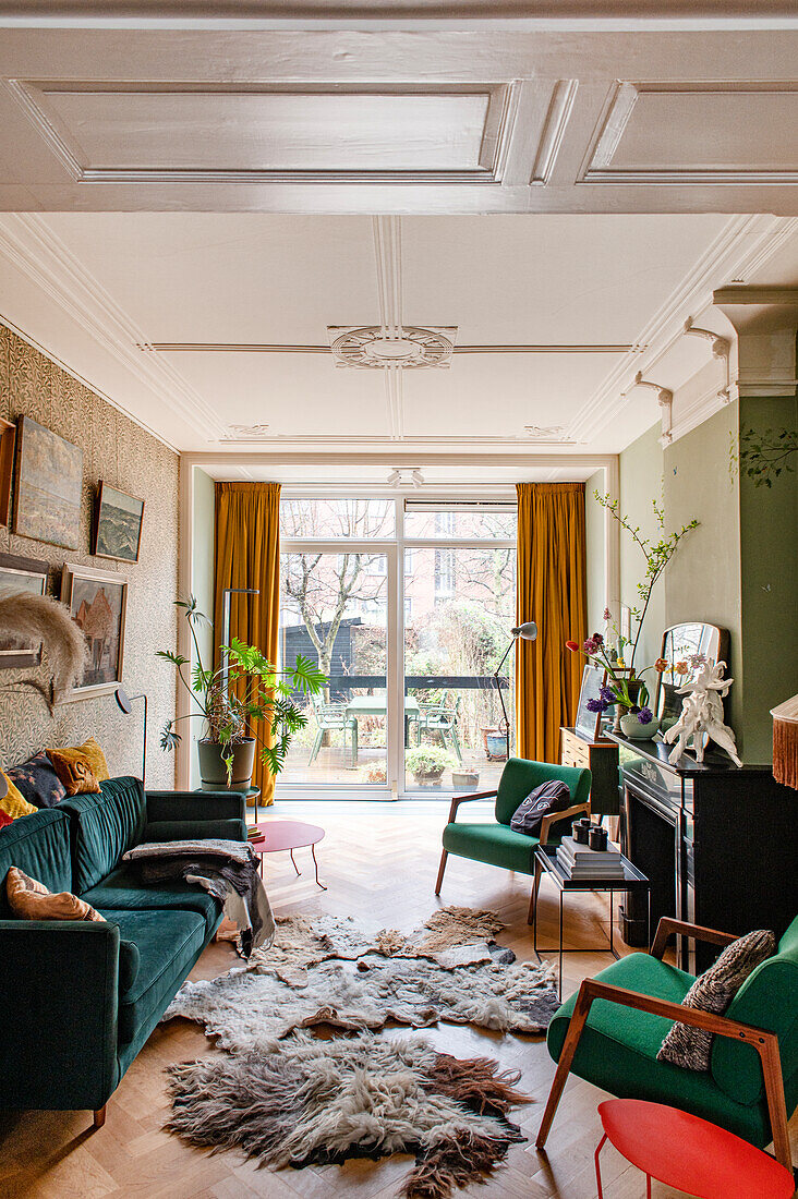 Wohnzimmer mit Holzparkett, Samtsofa und Fellteppichen, Blick auf Terrasse