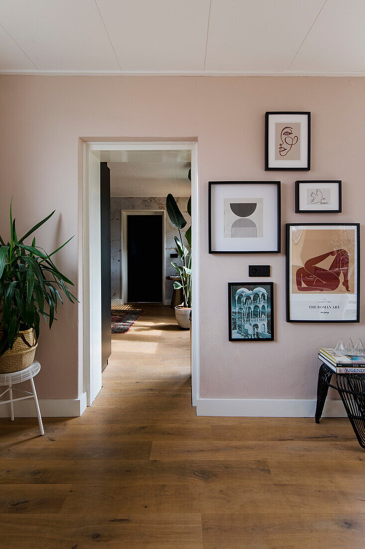 Hallway with wooden floor and modern picture frames on a pink wall