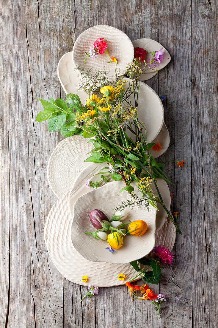 Weisse Keramik mit Kräutern, Blüten und Mini-Auberginen