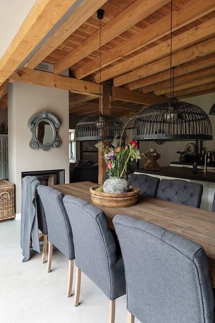 Wooden dining table with grey upholstered chairs and cage pendant lights