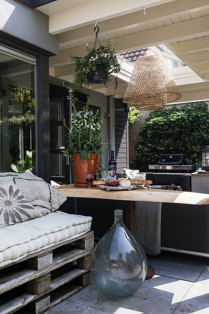 Comfortable seating area on the terrace with pallet sofa, wooden table and plants