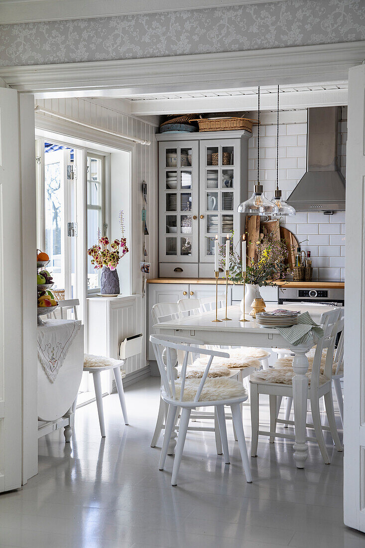 Bright dining area with white furniture, candles and flowers