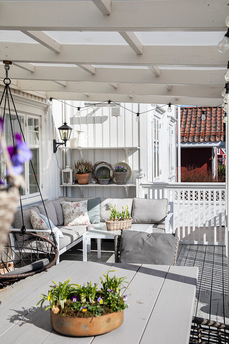 Terrasse mit Sitzgruppe und Frühlingsblumen unter Pergola