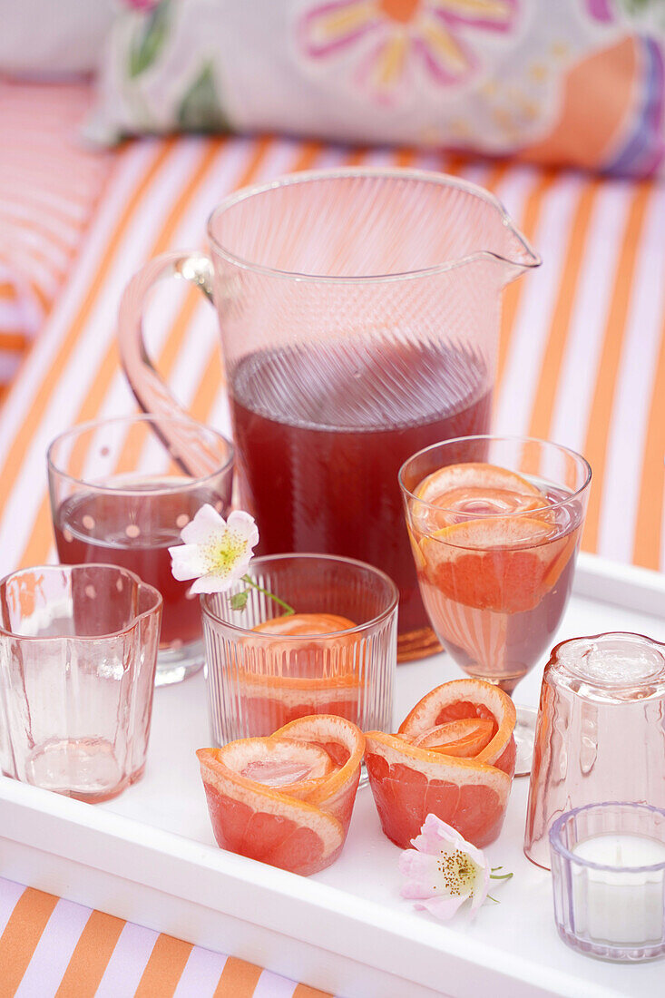 Pitcher and glasses with drinks on a tray, decorated with flowers