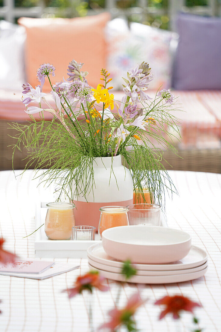 Blumenstrauß mit gemischten Sommerblumen und Kerzen auf Gartentisch