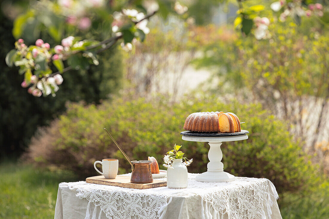 Bundt cake and oriental coffee pot on a laid table in the spring garden