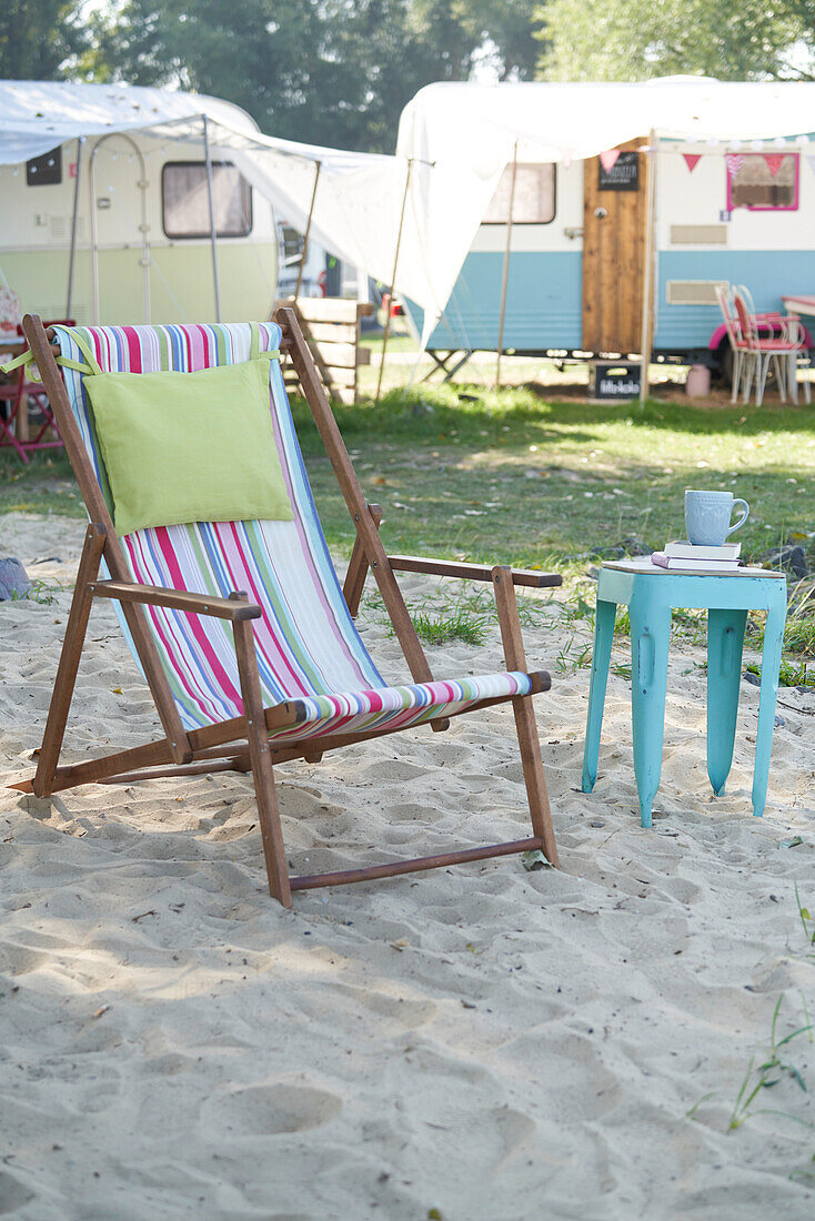 Folding chair with colorful striped fabric cover and side table on campsite