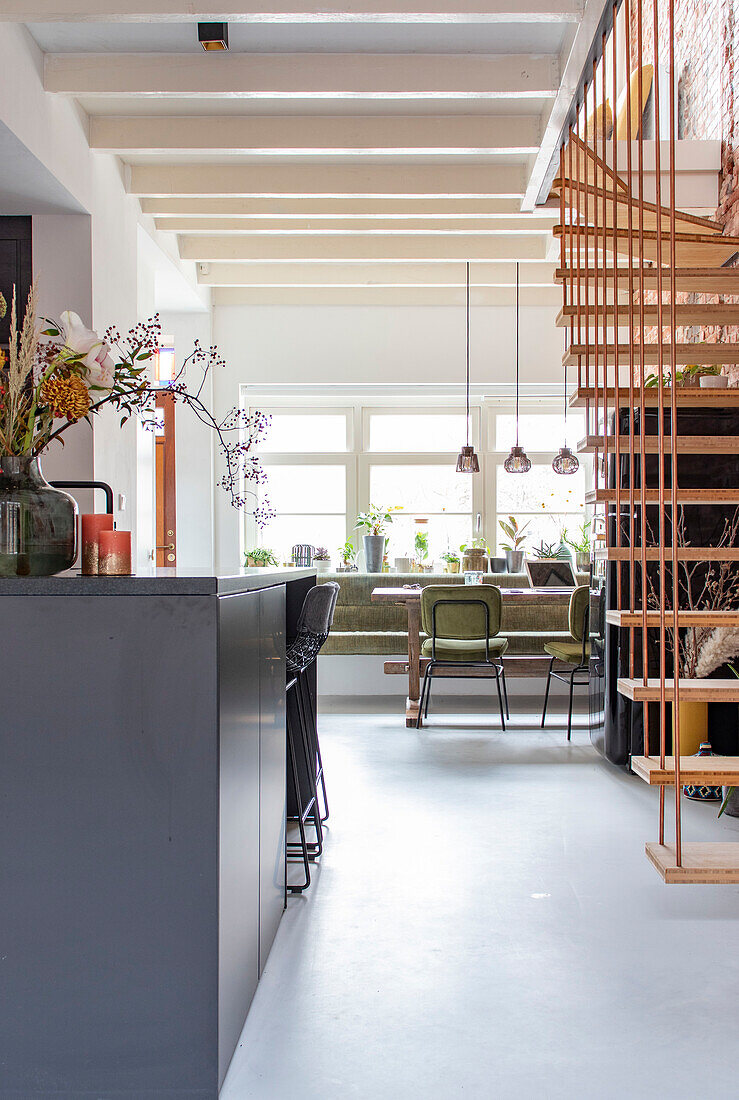 Bright open kitchen, dining area and hanging wooden staircase in loft style