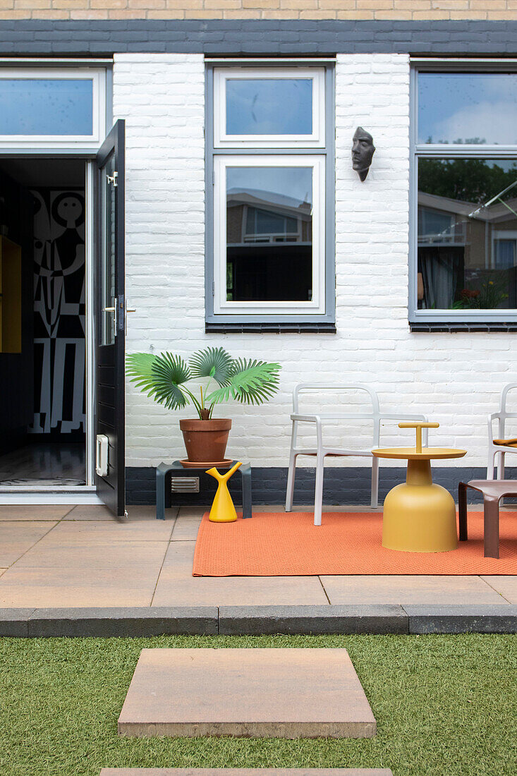 Moderne Terrasse mit orangefarbenem Teppich, Kunststoffmöbeln und Pflanztopf