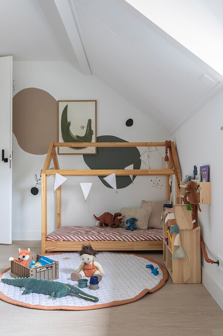 Kinderzimmer mit Hausbett und Spielzeug unter Dachschräge