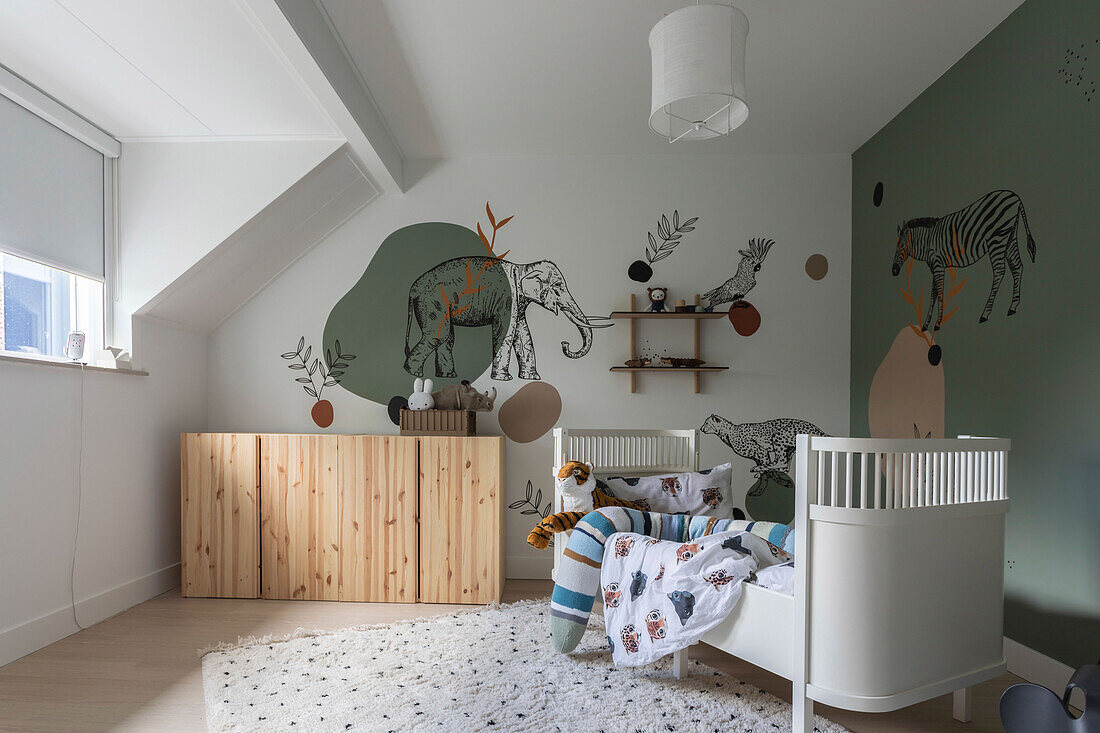 Kinderzimmer mit Tiermotiven an den Wänden und weißem Kinderbett