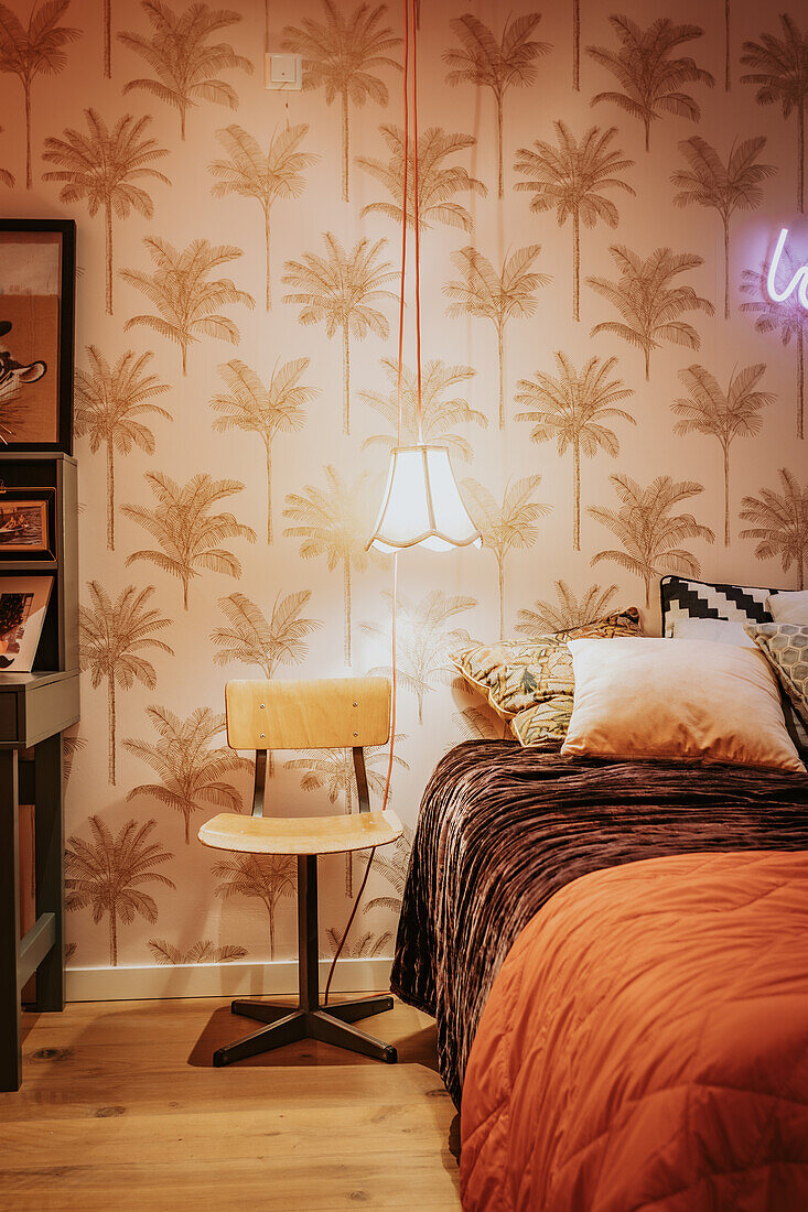 Bedroom with palm wallpaper, wooden chair and retro lamp