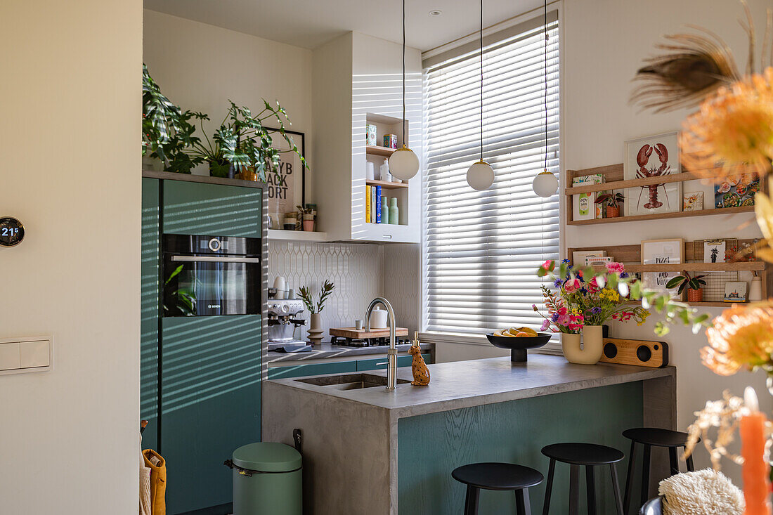 Kitchen with green cabinets, concrete worktop and plants