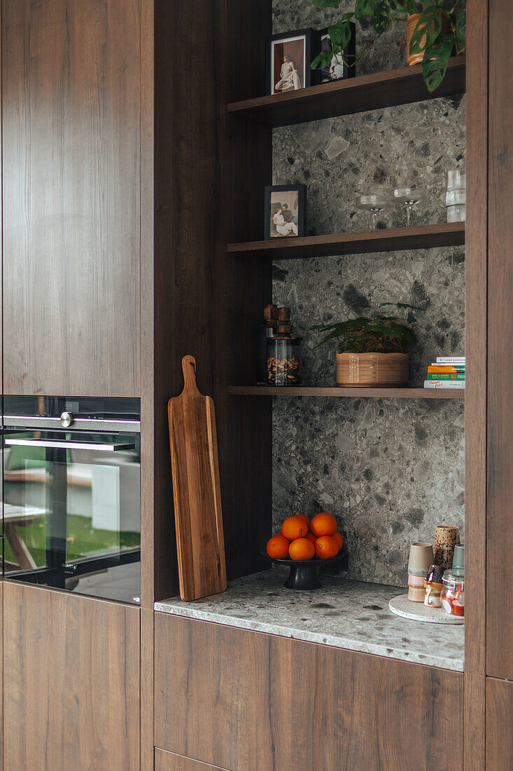 Kitchen with niche shelving, marble wall and fresh oranges on counter