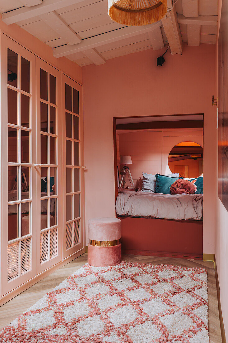 Bedroom in shades of pink with built-in wardrobes and patterned carpet