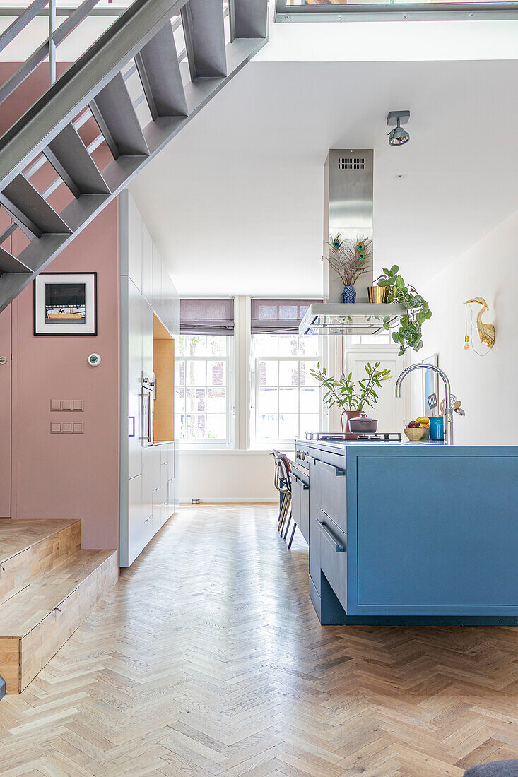 Kitchen with blue island, herringbone parquet flooring and staircase