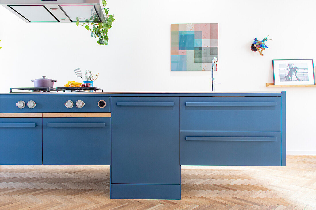 Kitchen island in blue with integrated appliances, parquet flooring