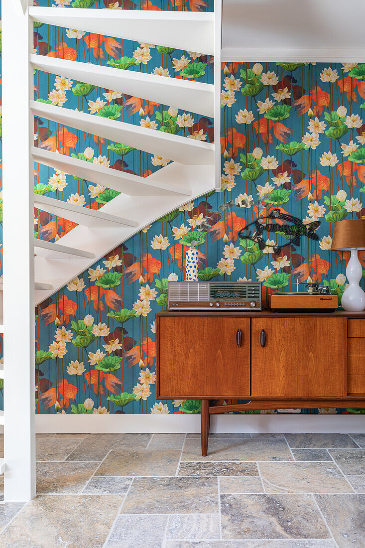 Floral wallpaper and mid-century furniture in the hallway with spiral staircase