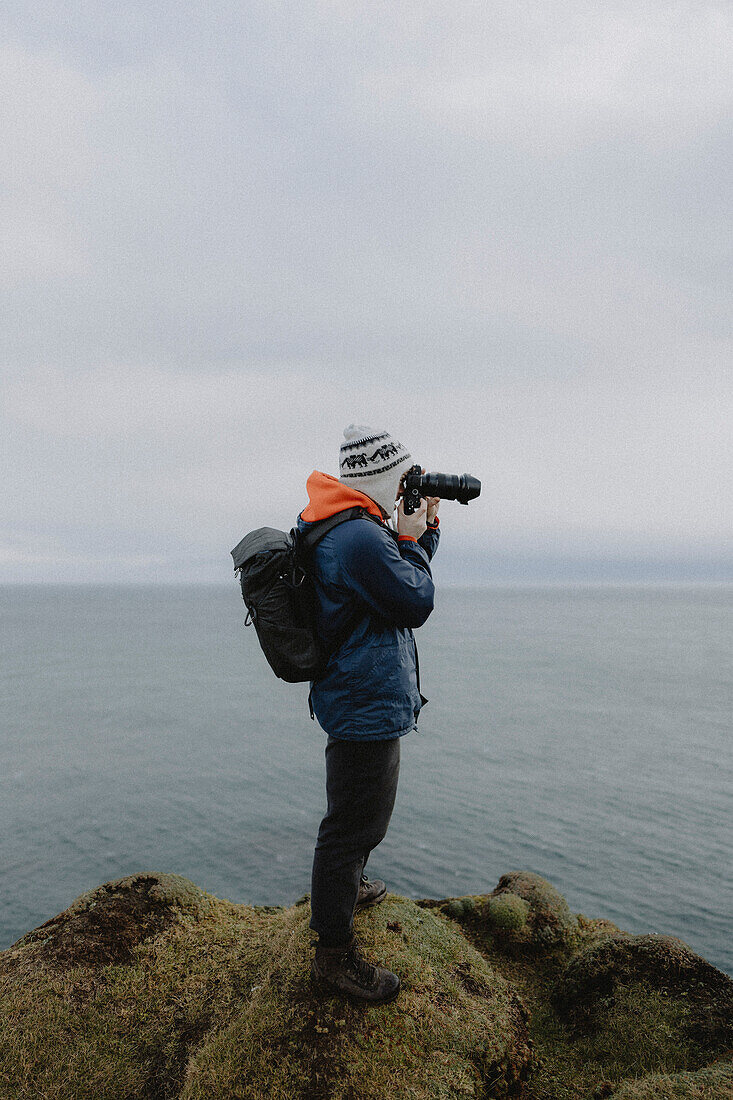 Photographer with camera on cliff above sea, Duncansby, Scottish Highlands, Scotland\n