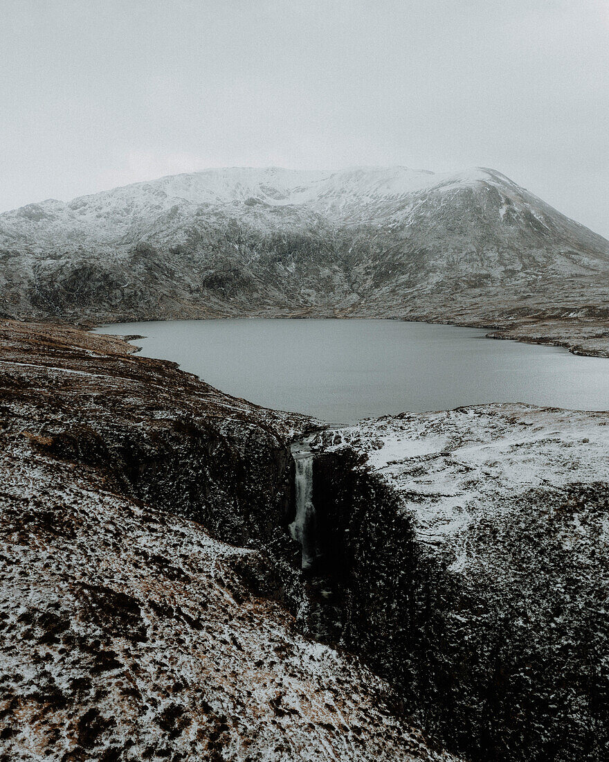 Waterfall and lake in snowy mountain landscape, Assynt, Sutherland, Scotland\n