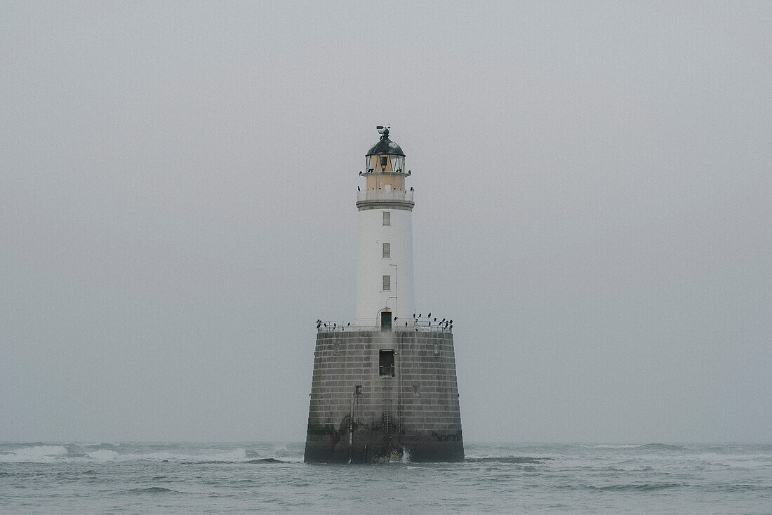 Lighthouse in sea under overcast sky, Rattray, Aberdeenshire, Scotland\n