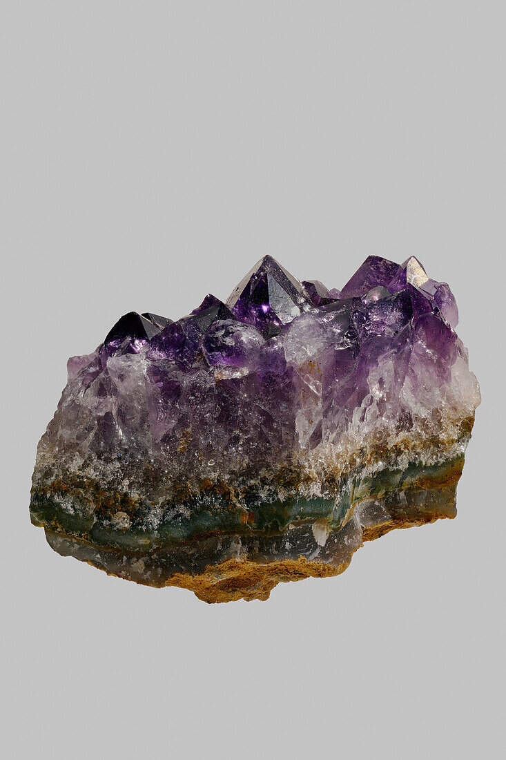 Nahaufnahme texturierter violetter uruguayischer Amethystkristall auf grauem Hintergrund