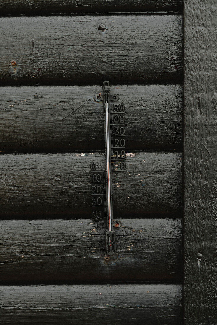 Gusseisernes Thermometer an schwarzer Hauswand