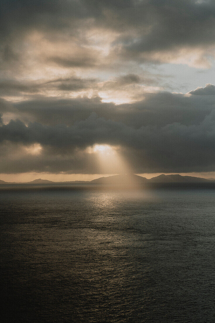 Sonnenstrahl am dramatischen Himmel über dem ruhigen Meer bei Sonnenuntergang, Neist Point, Isle of Skye, Schottland