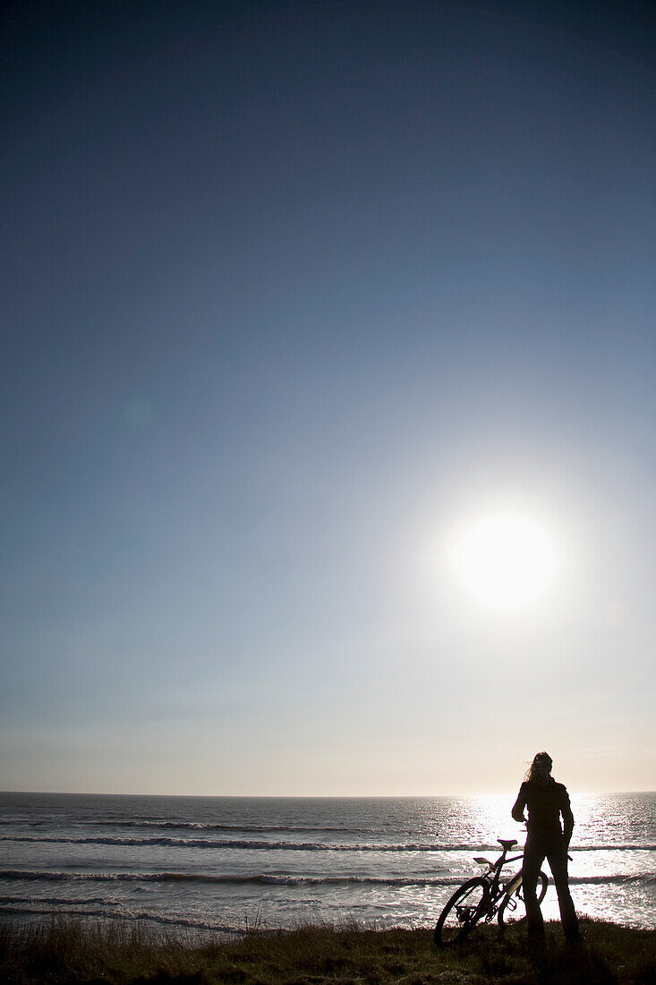 Young woman enjoying the ocean view with bicycle\n