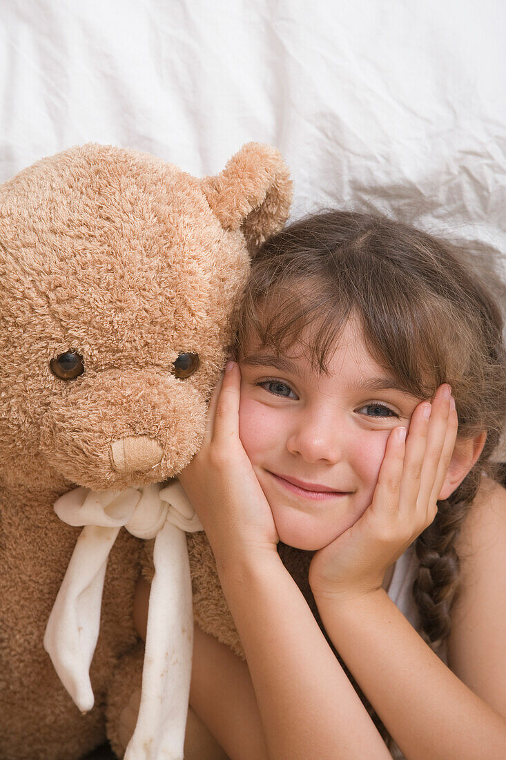 Close up of young girl with teddy bear smiling\n