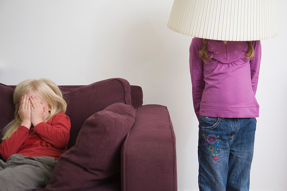 Two young girls playing hide and seek\n