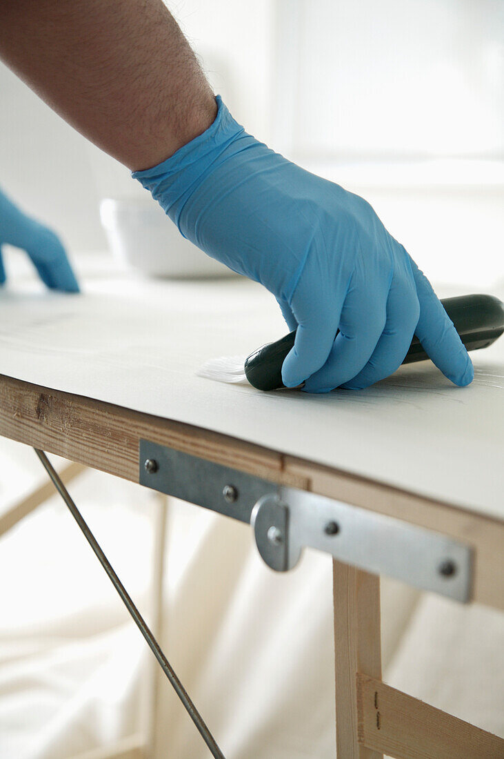 Close up of man's hands applying wallpaper paste\n