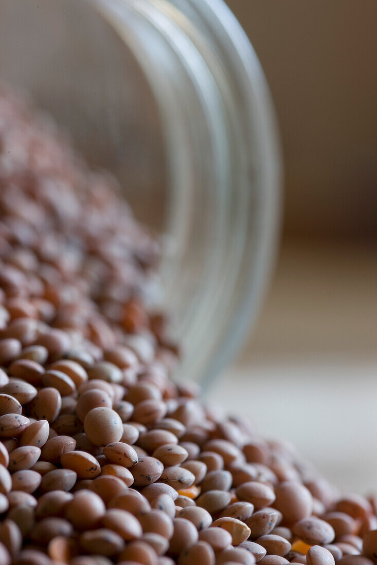 Close up of lentils pouring out of glass jar\n