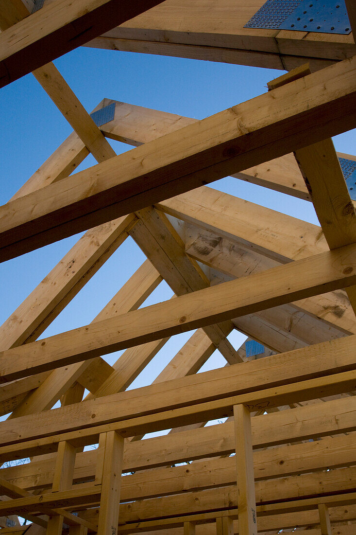 Roof beams of house under construction against blue sky\n