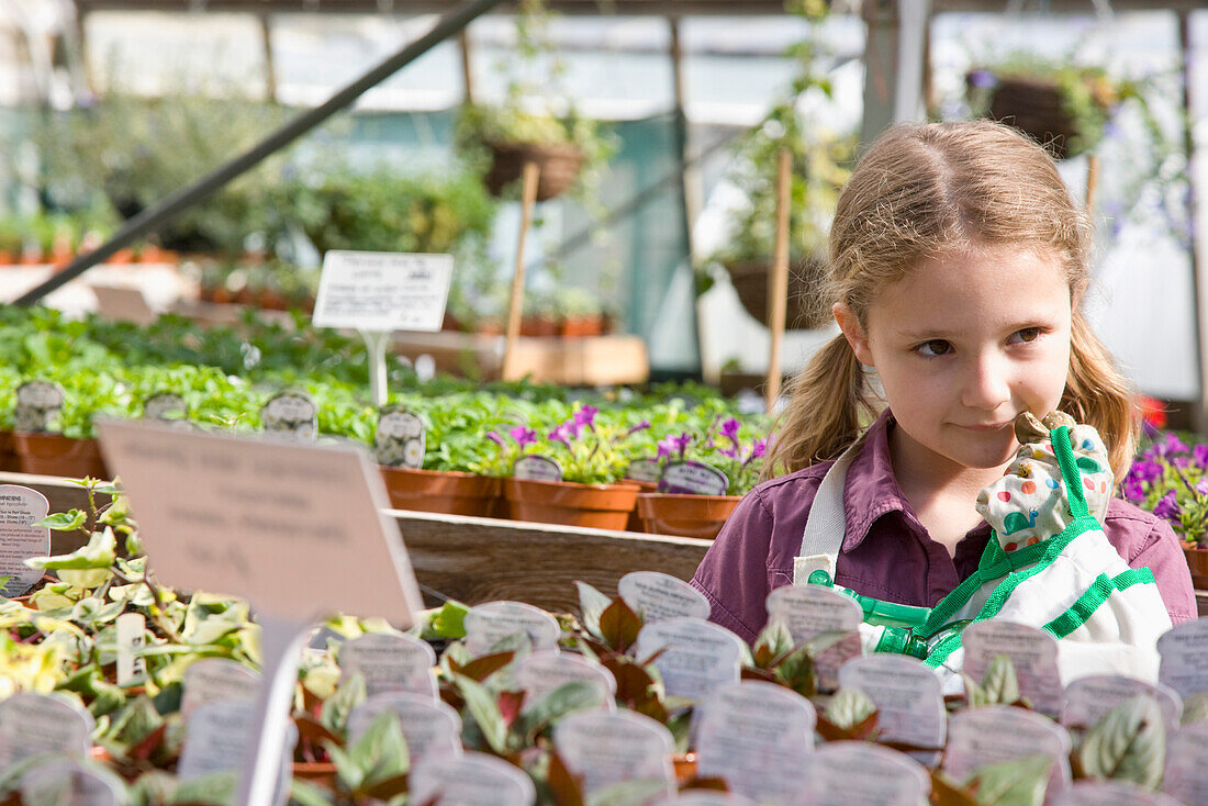 Portrait of young girl amongst flowerpots inside greenhouse\n