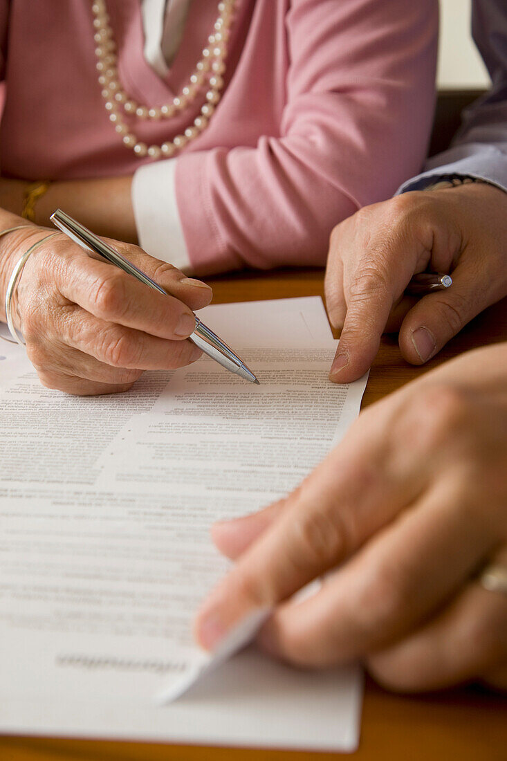 Close up of man and woman hands signing documents\n