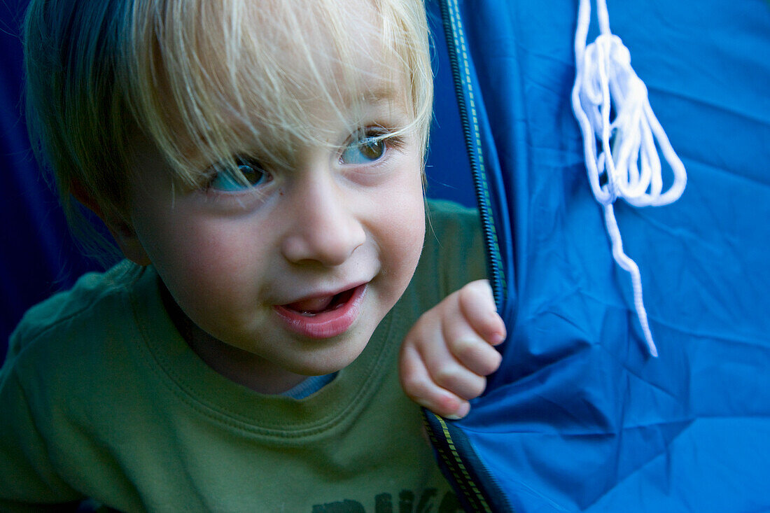 Junger blonder Junge spielt in einem Zelt