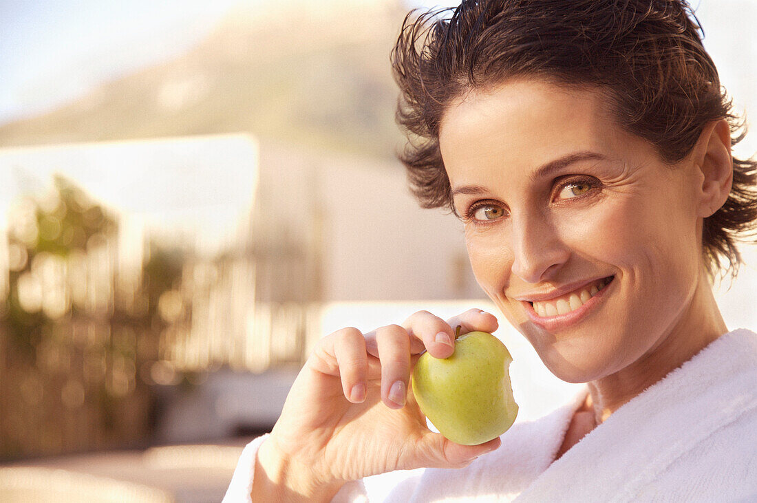 Smiling woman eating apple\n