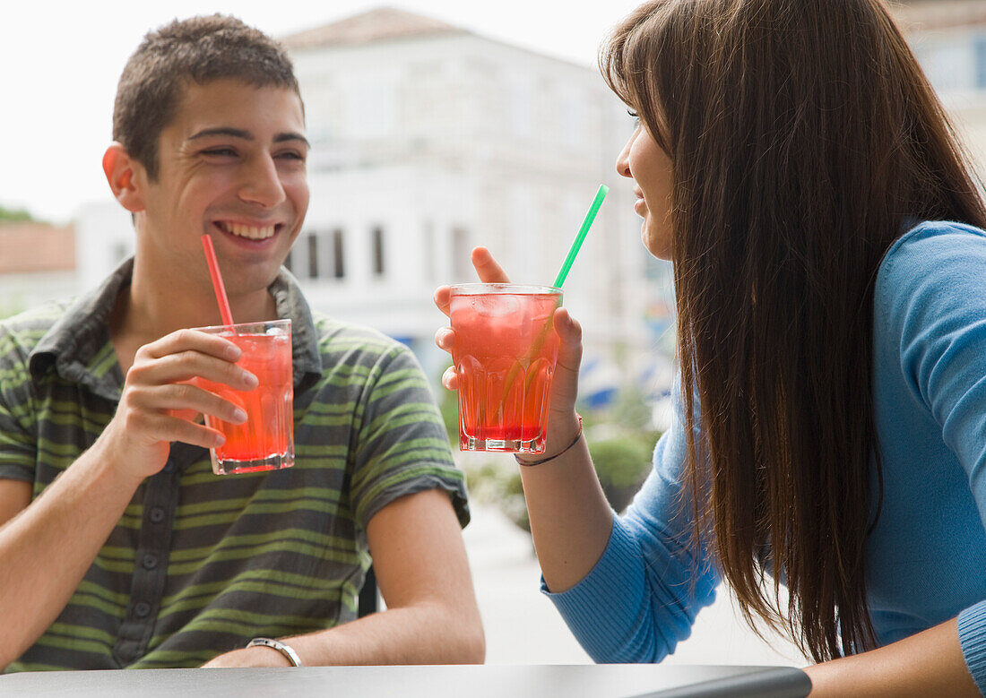 Porträt eines jungen Paares, das sitzt und Cocktails trinkt