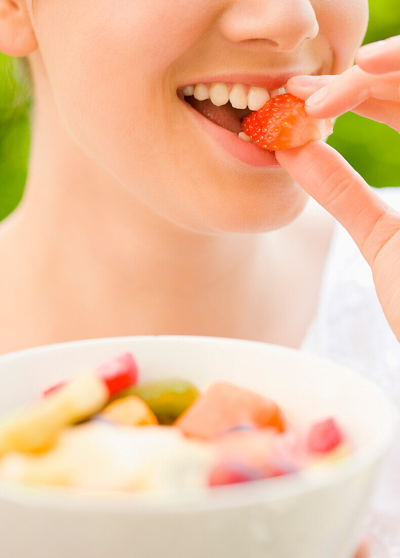 Close up of a young woman biting a strawberry\n