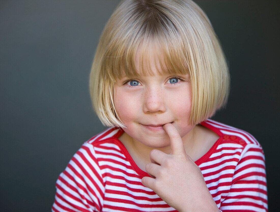 Portrait of a young girl with finger in her mouth\n