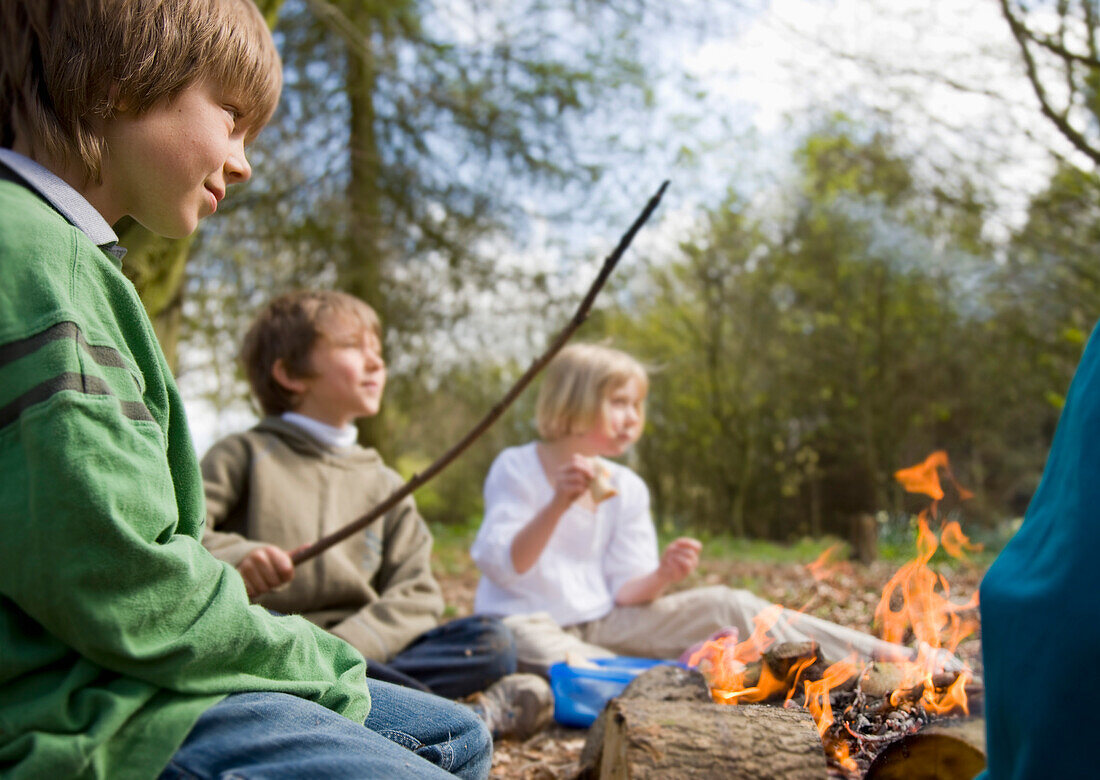 Kinder sitzen um ein Lagerfeuer