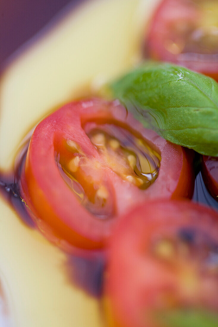 Kirschtomaten und Basilikumblätter in Olivenöl und Balsamico-Dressing
