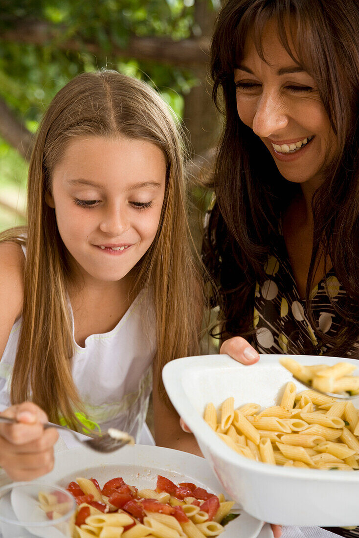 Mother serving pasta to daughter\n