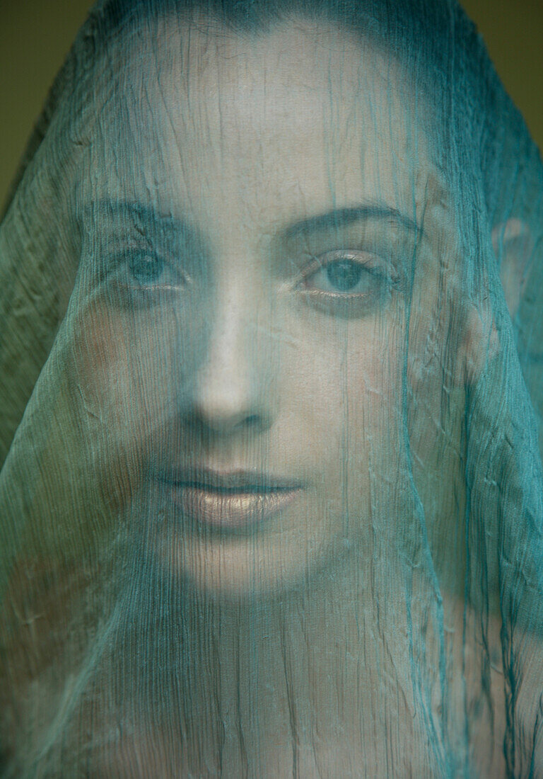Portrait of young beautiful woman with light green veil\n