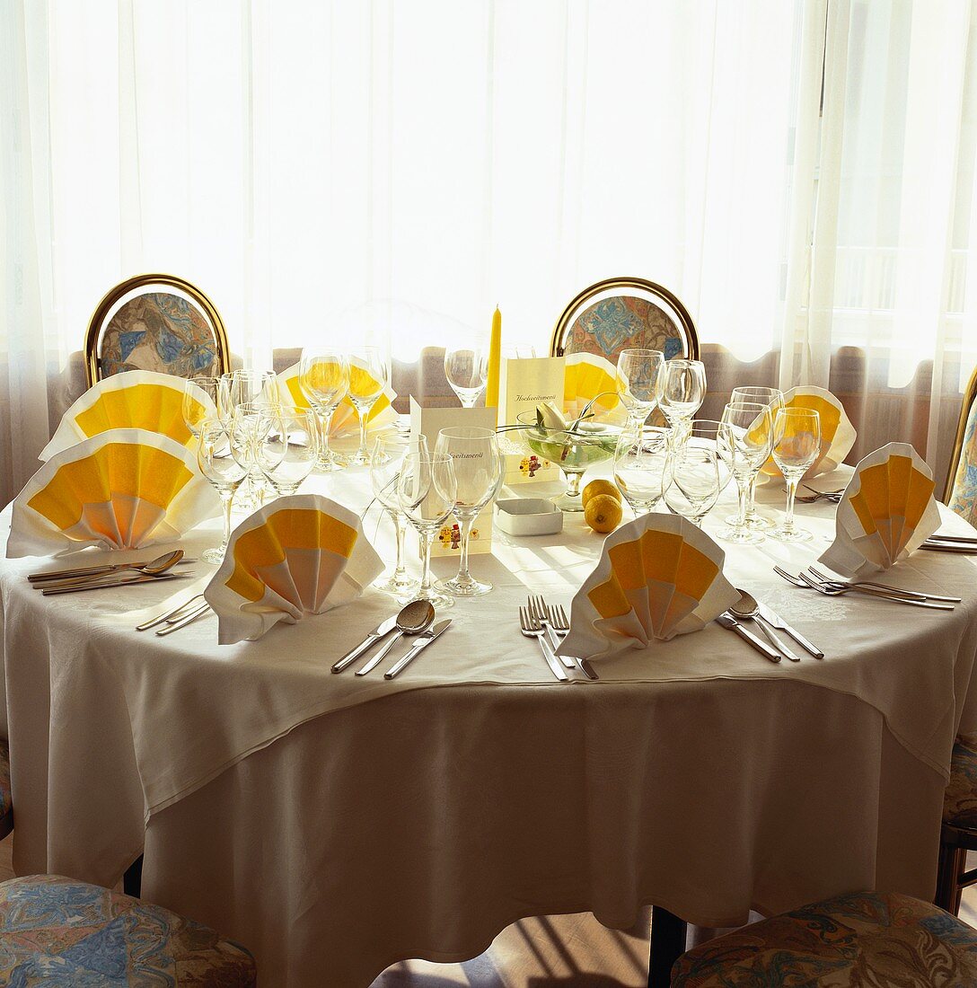 Gedeckter runder Hochzeitstisch mit weiss-gelben Servietten