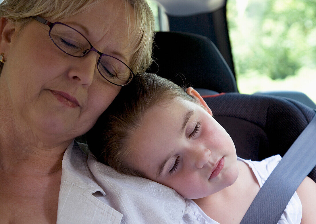 Grandmother and  granddaughter sleeping inside car\n